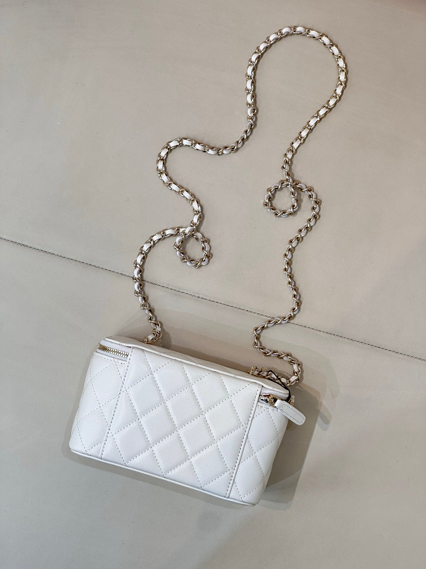 Chanel white quilted mini bag with chain strap, zip top, CC logo detail.