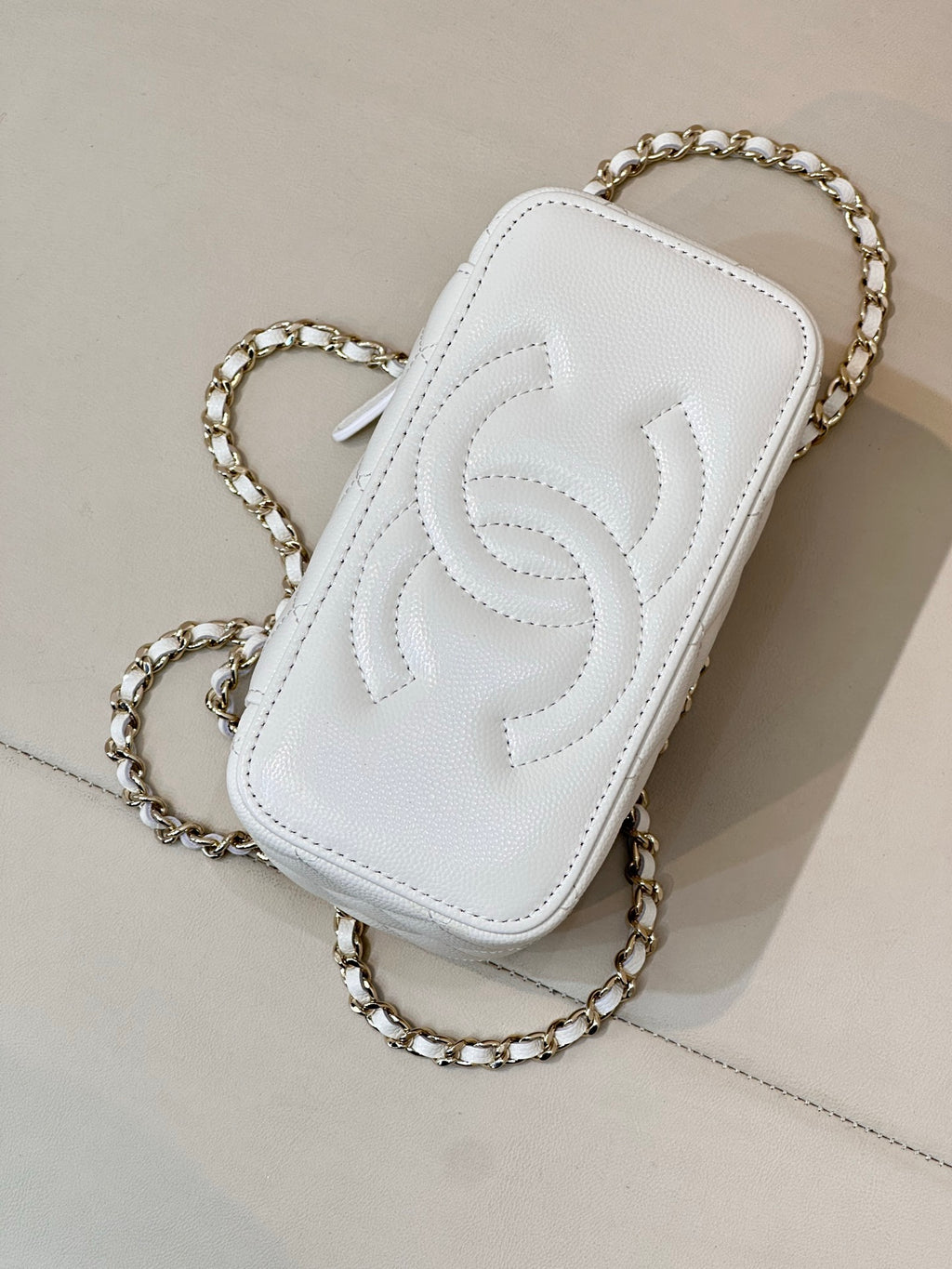Chanel white leather mini bag with embossed CC logo, chain strap, zip top.