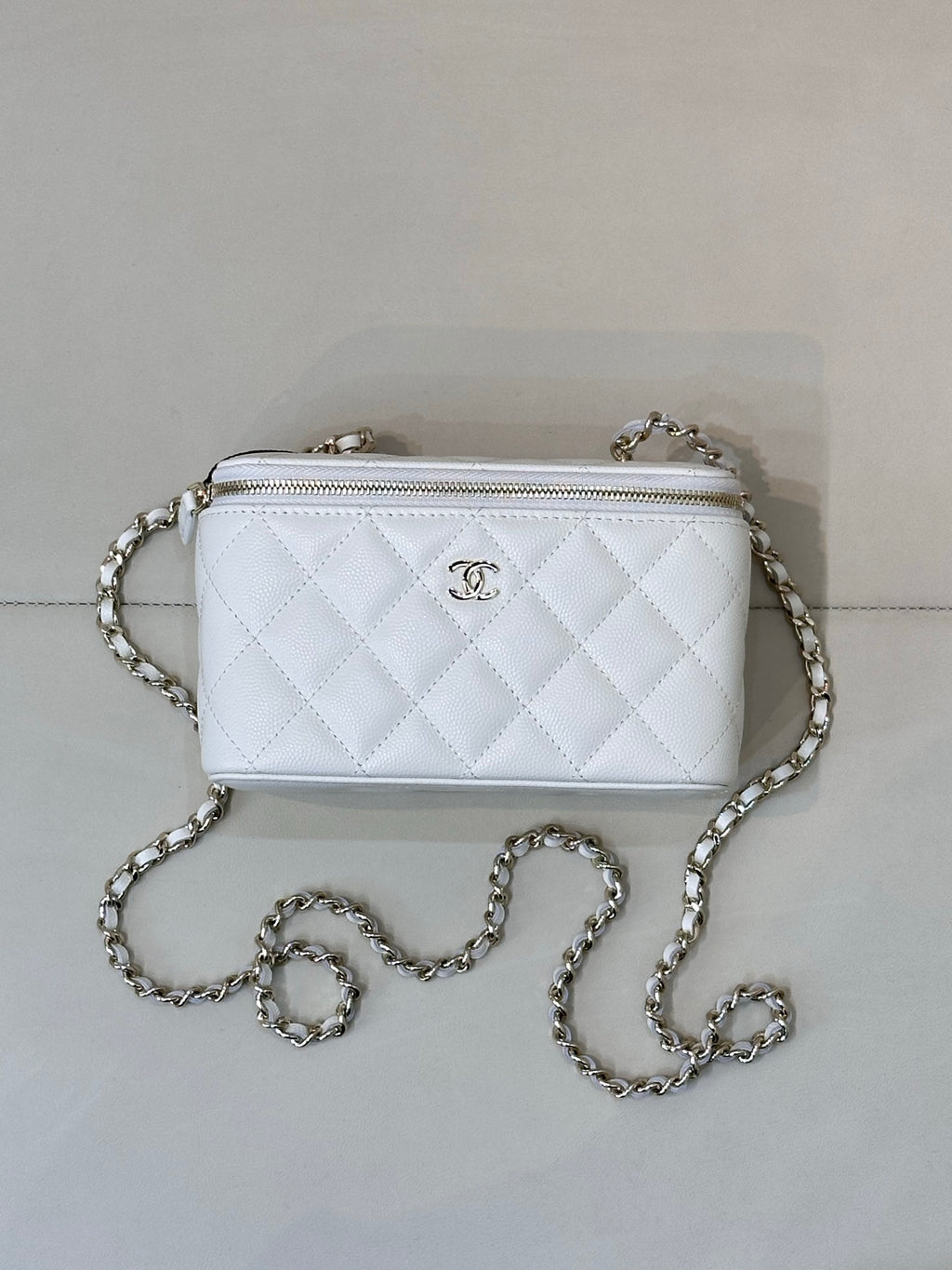 Chanel white quilted crossbody bag, front CC logo, chain strap, zip top.