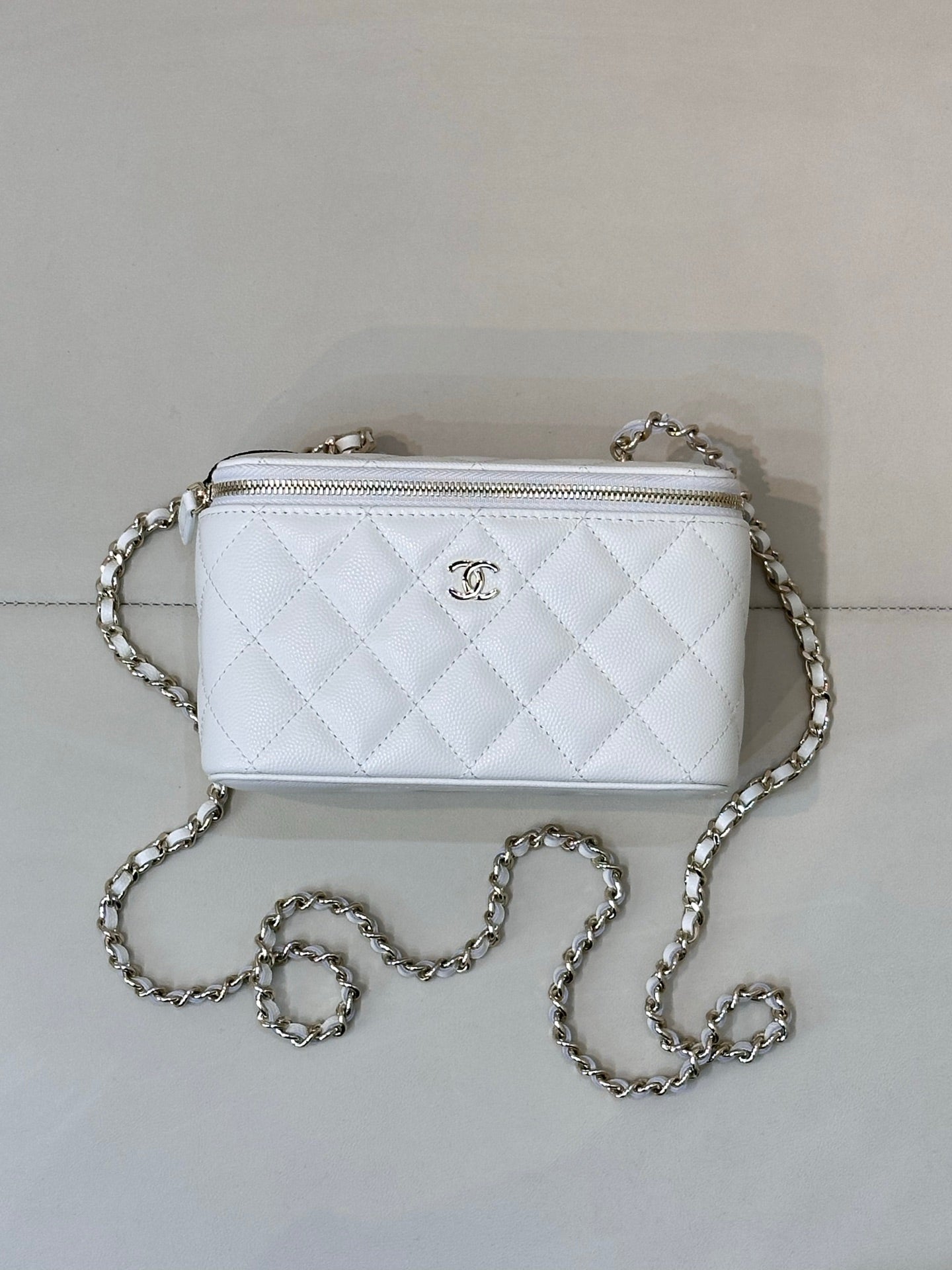 Chanel white quilted crossbody bag, front CC logo, chain strap, zip top.