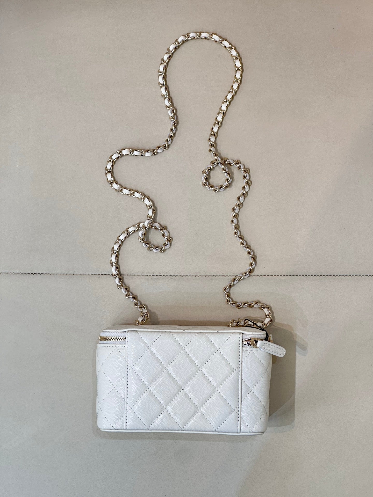 Chanel white quilted mini bag with chain strap and zip top, gold-toned hardware.