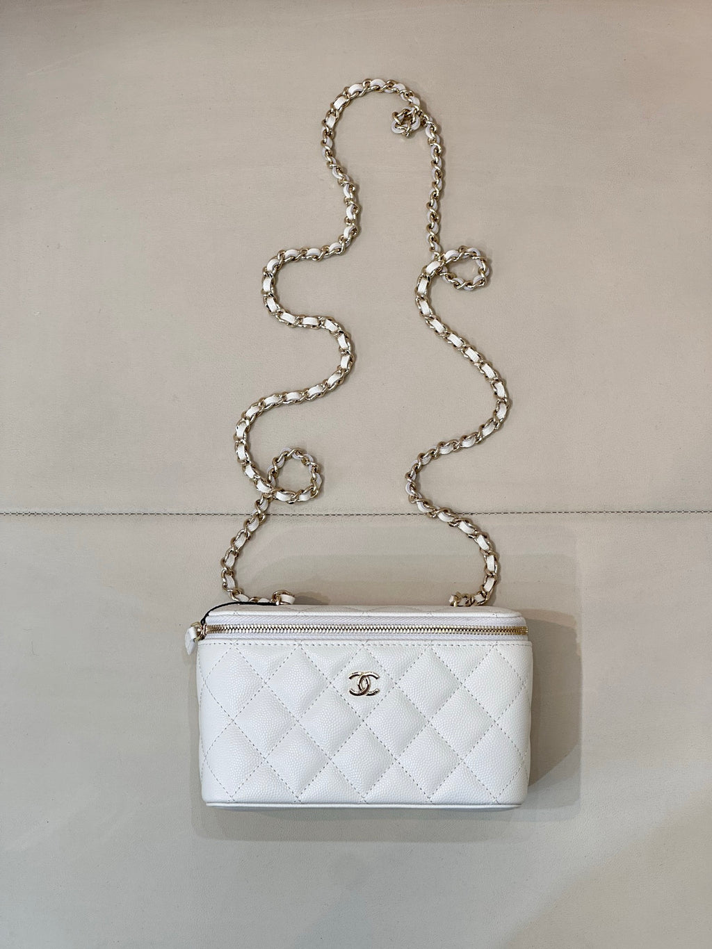 Chanel white quilted bag with diamond pattern, chain strap, zip top, CC logo.