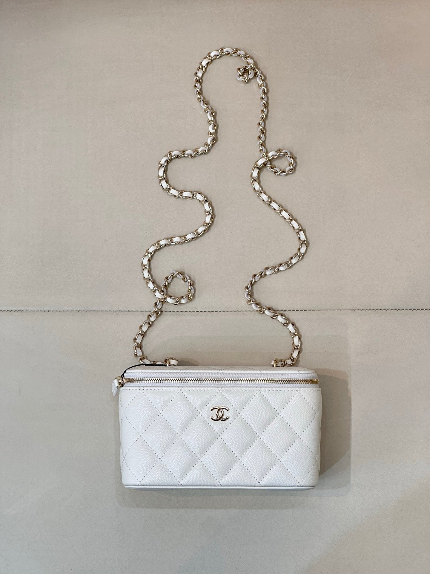 Chanel white quilted bag with diamond pattern, chain strap, zip top, CC logo.
