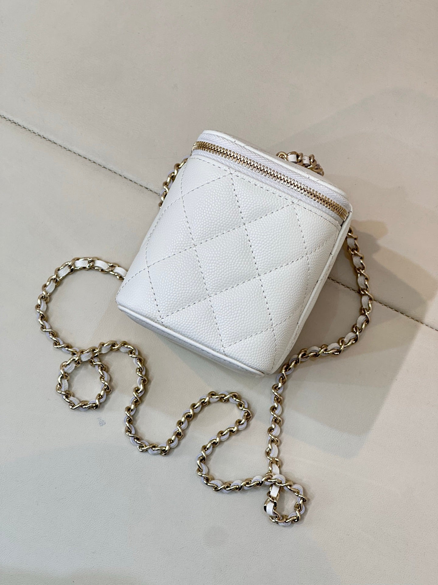 Chanel white quilted mini bag with chain strap, zip top, gold-toned hardware.