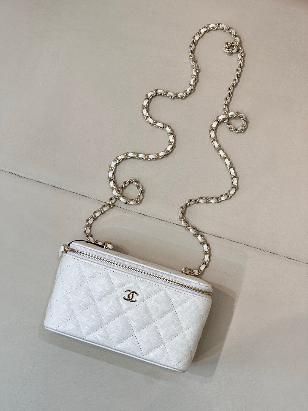 Chanel white quilted shoulder bag with zip top and chain strap, CC logo on front.