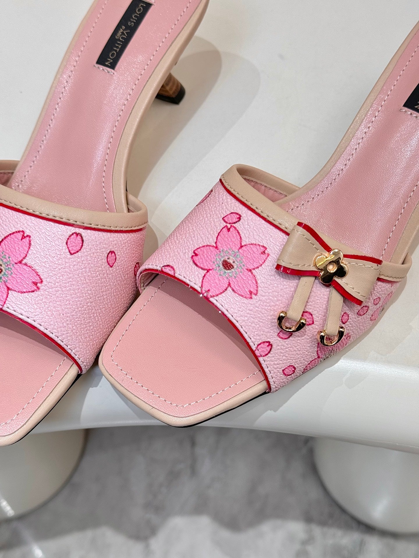Pink Louis Vuitton ladies mules close-up: floral strap with gold-tone buckle accent
