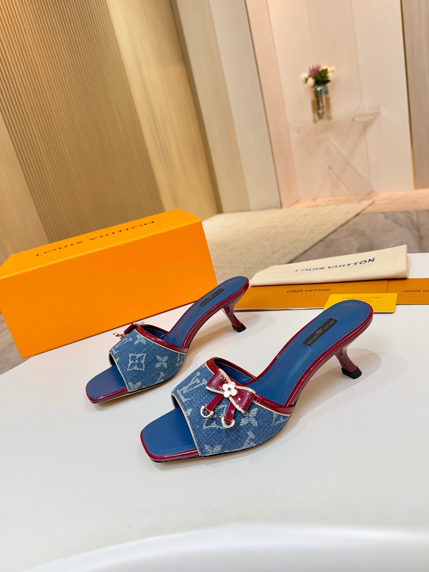 Louis Vuitton ladies blue monogram slide mules with red trim and bow buckle detail, standing view