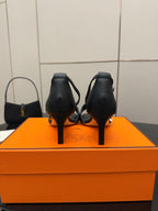 Black leather heeled sandals viewed from the back with slim heel and strap overlap