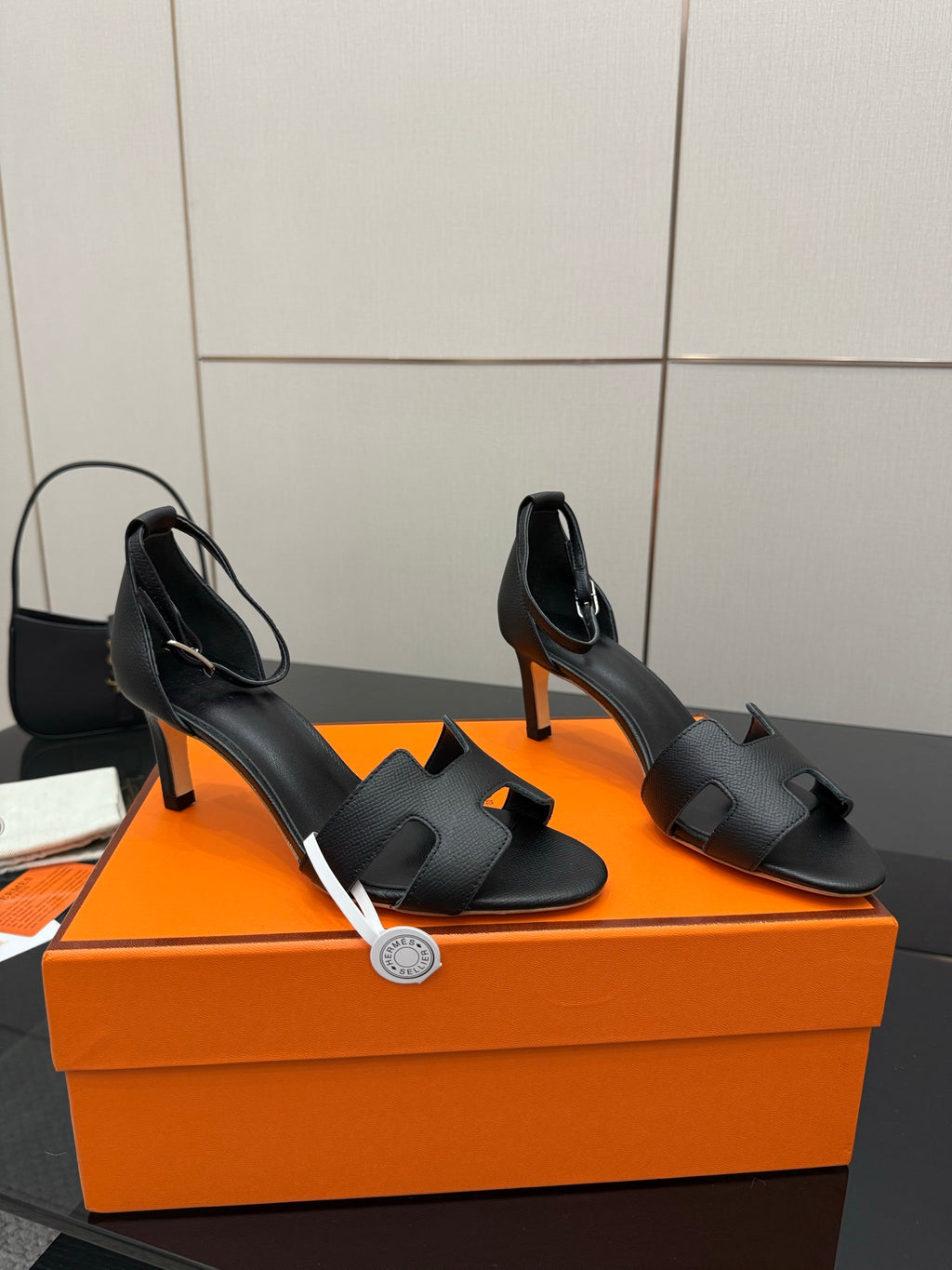 Pair of black leather heeled sandals with open sides, square toe, and slim heel
