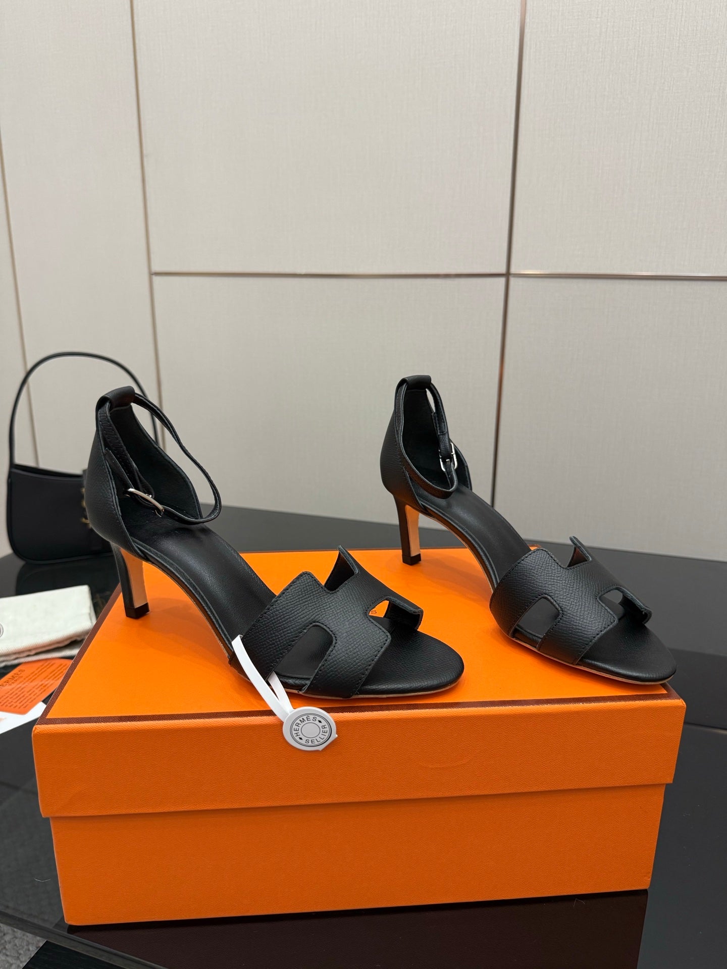Pair of black leather heeled sandals with open sides, square toe, and slim heel