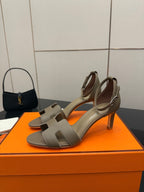 Light gray heeled sandal with ankle strap, open toe, and block heel.