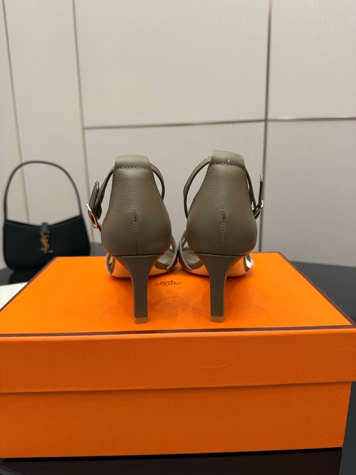 Light gray heeled sandals, rear view with ankle strap and covered heel.