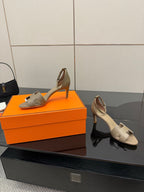 Light gray heeled sandals with open toe, ankle strap, and side cutouts.