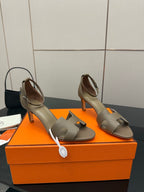 Light gray heeled sandals with open toe, ankle strap, and sculpted block heel.