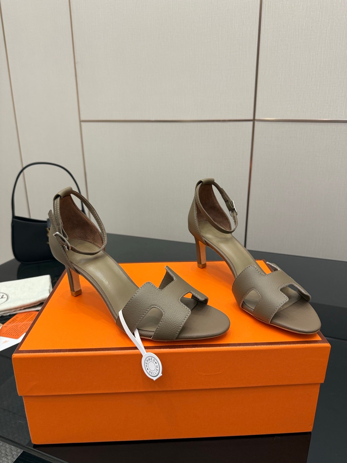 Light gray heeled sandals with open toe, ankle strap, and sculpted block heel.