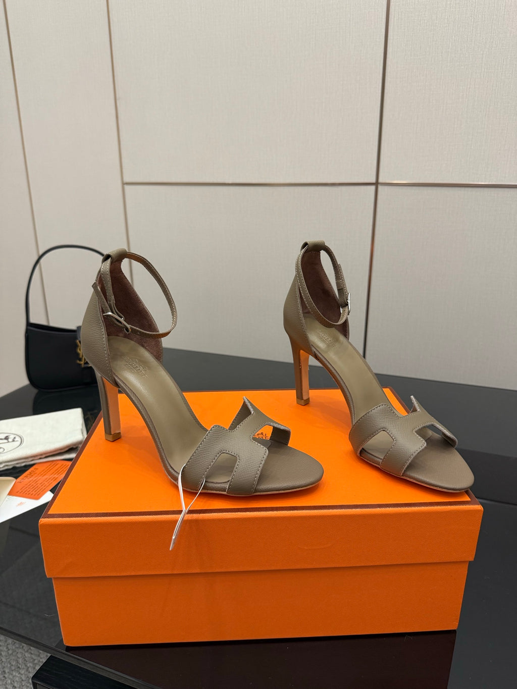 Ladies heeled sandals in light gray on an orange box, side view with ankle strap