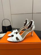 White open-toe heeled sandals with ankle strap and T-bar front