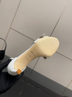 White sandal outsole and heel underside view, with signature marking on footbed