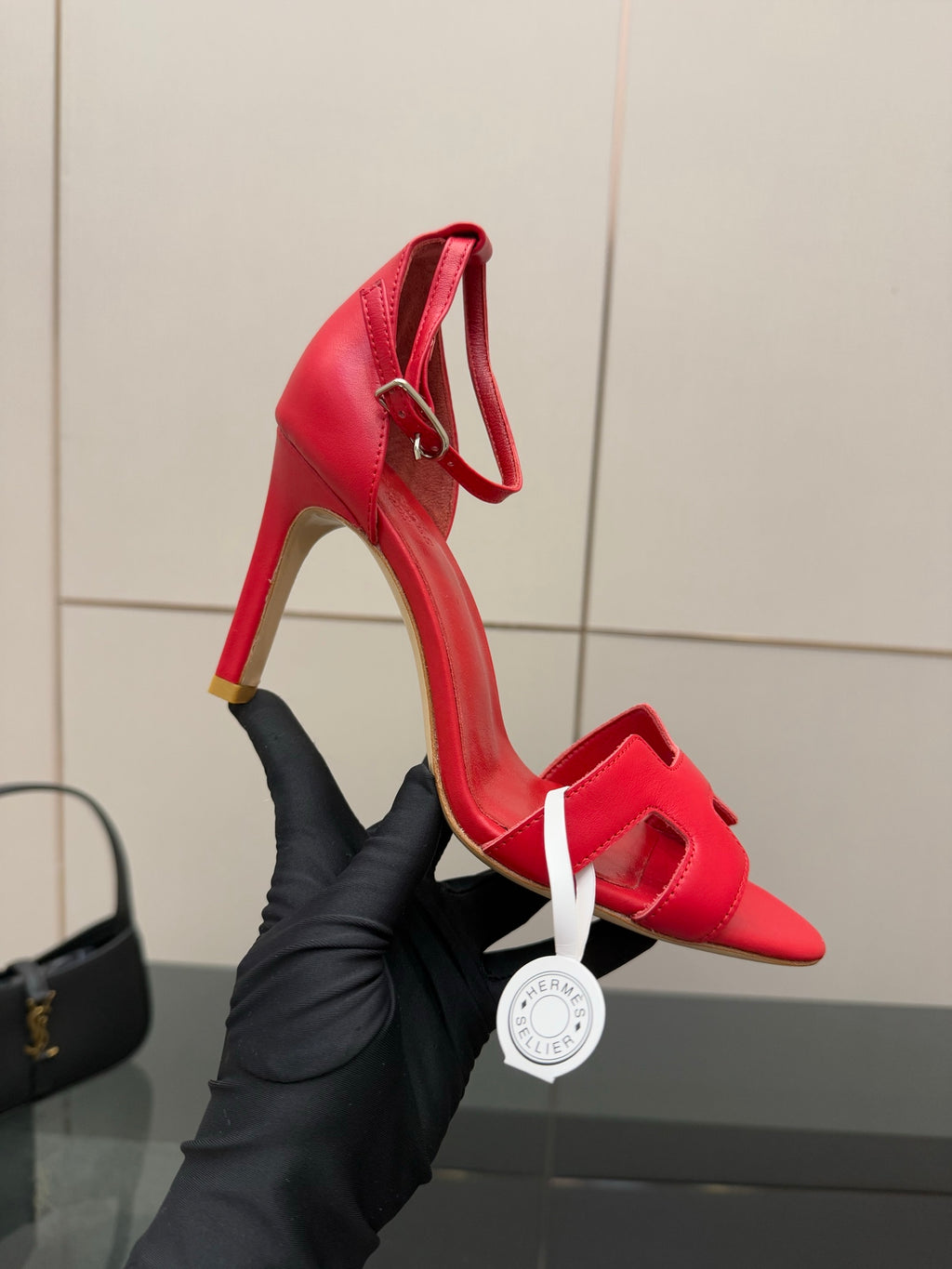 Hermes red slingback sandal in hand, showing ankle strap and stiletto heel
