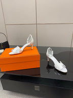 White heeled sandals on display, open toe with ankle strap and cutout straps