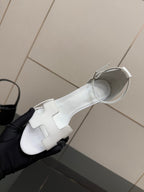 White heeled sandal with ankle strap, open toe, and curved cutout design