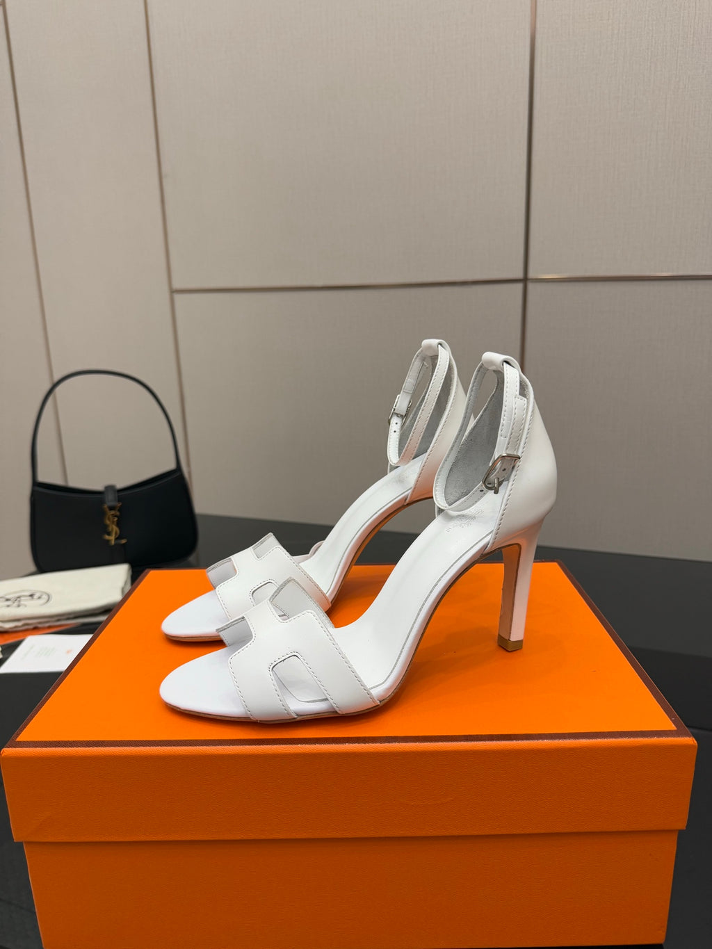 Hermes women's white heeled sandals on orange box, side profile