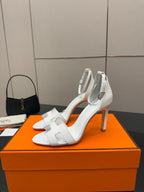 Hermes women's white heeled sandals on orange box, side profile
