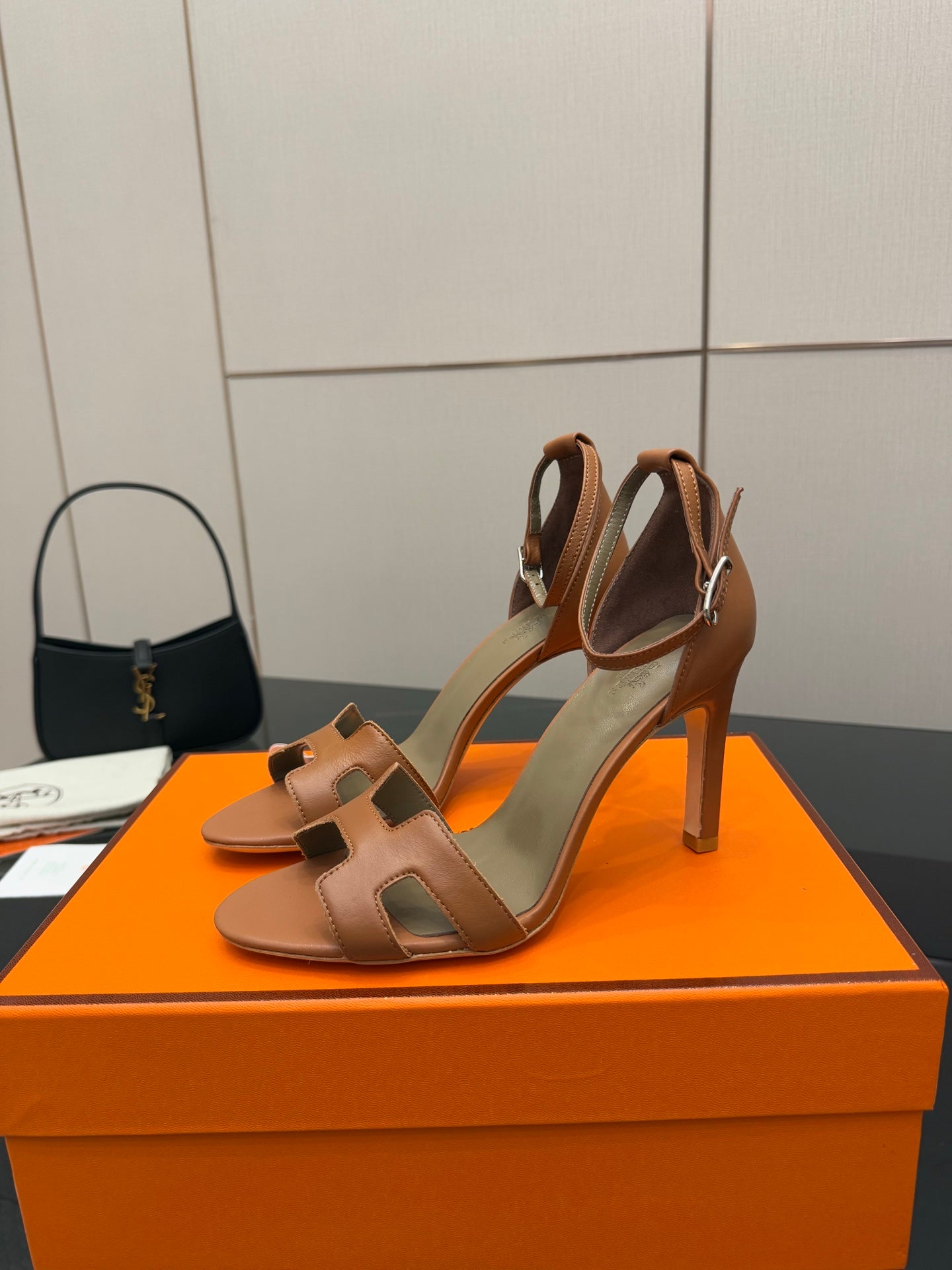 Tan leather heeled sandals set on orange box, showing front and back profile