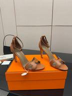 Tan leather heeled sandals with buckle-style straps and slim high heel
