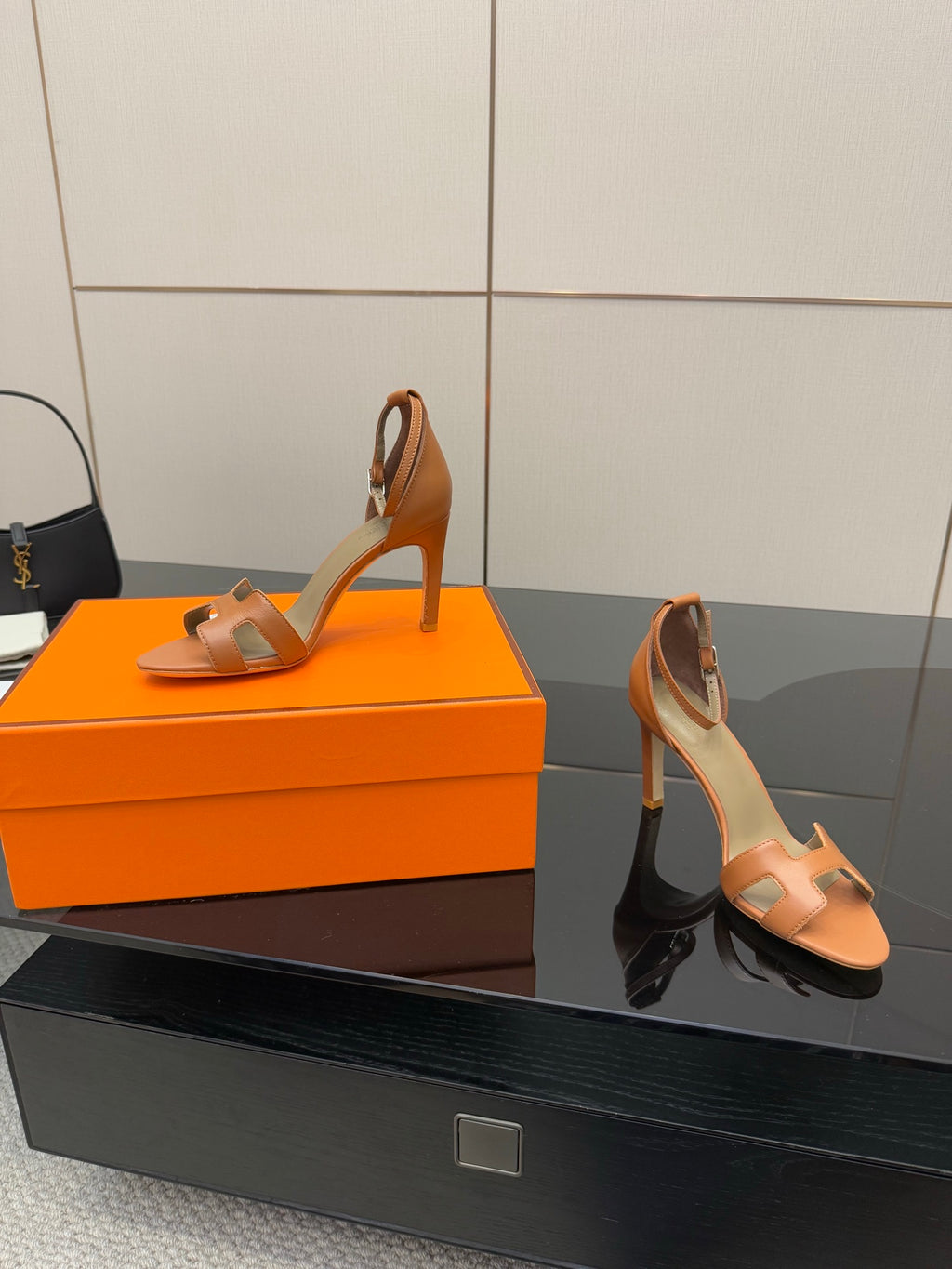 Tan leather heeled sandals, side view on orange box and on display surface