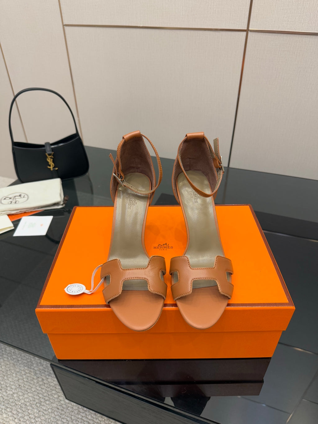 Tan leather heeled sandals with two strap cutouts on an orange presentation box
