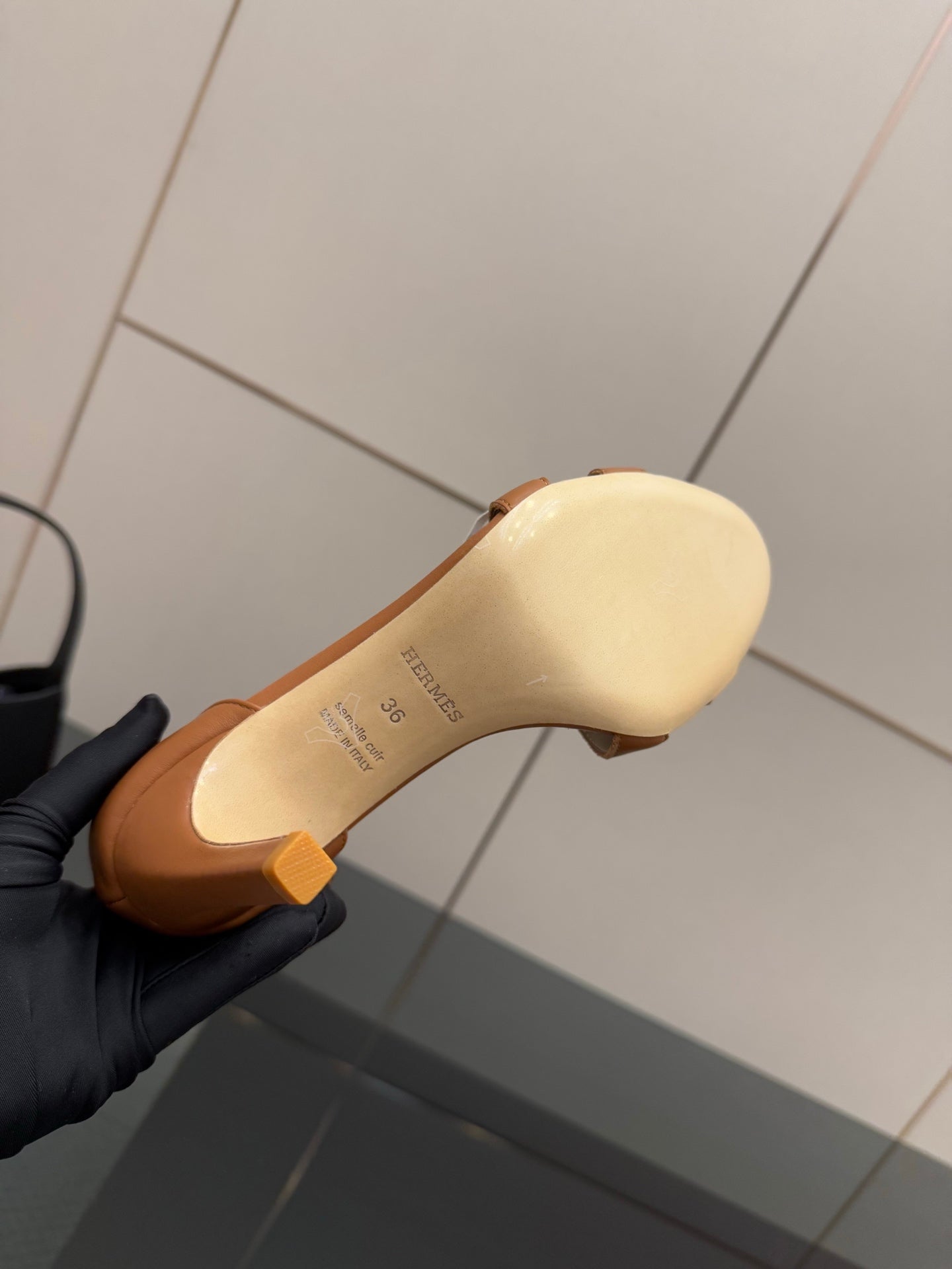 Tan leather insole of a heeled sandal, with branding text near the arch