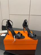 Women's black leather heeled sandals with wide straps and slim stiletto heel on box