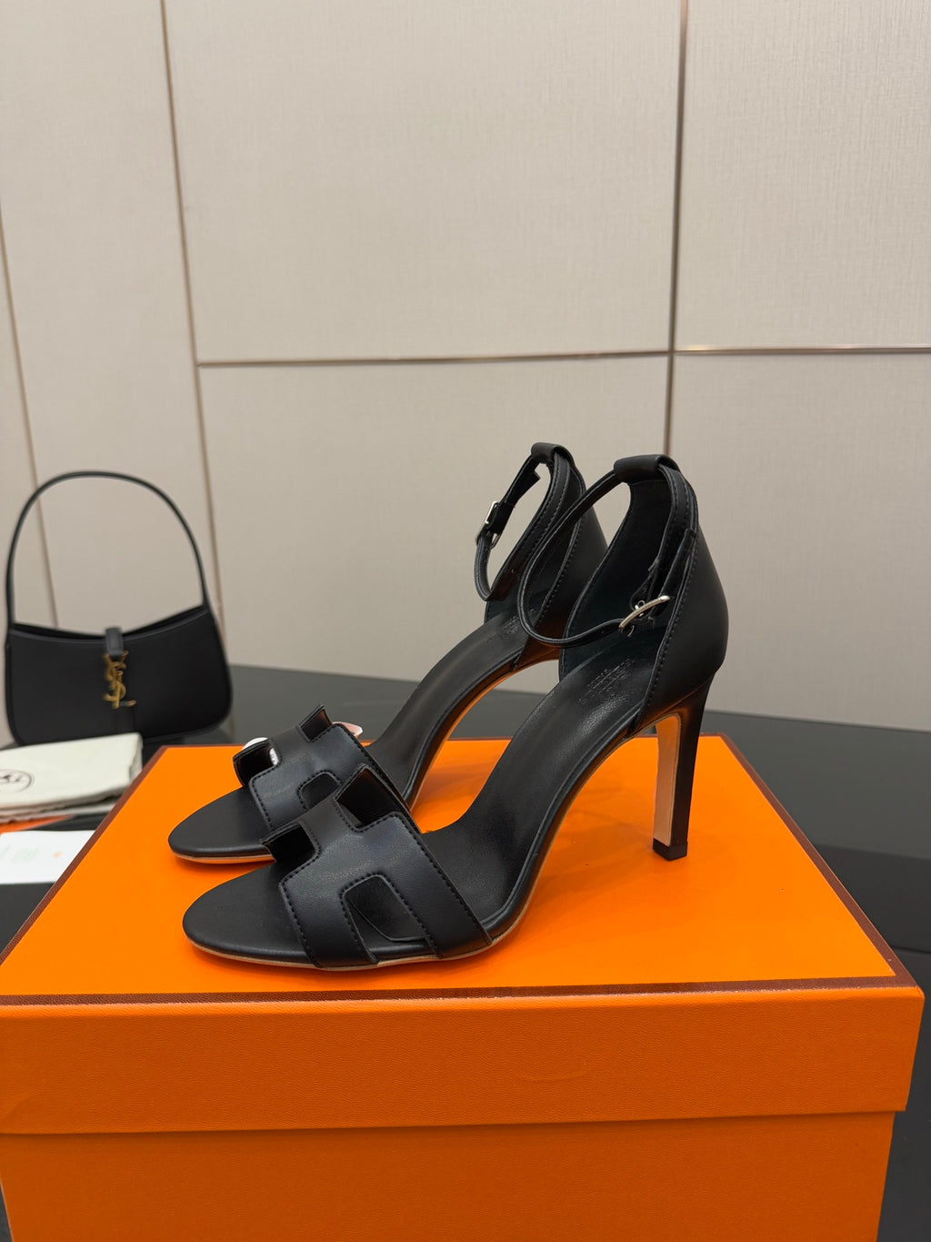 Women's black leather heeled sandals with wide buckle straps and slender stiletto heel