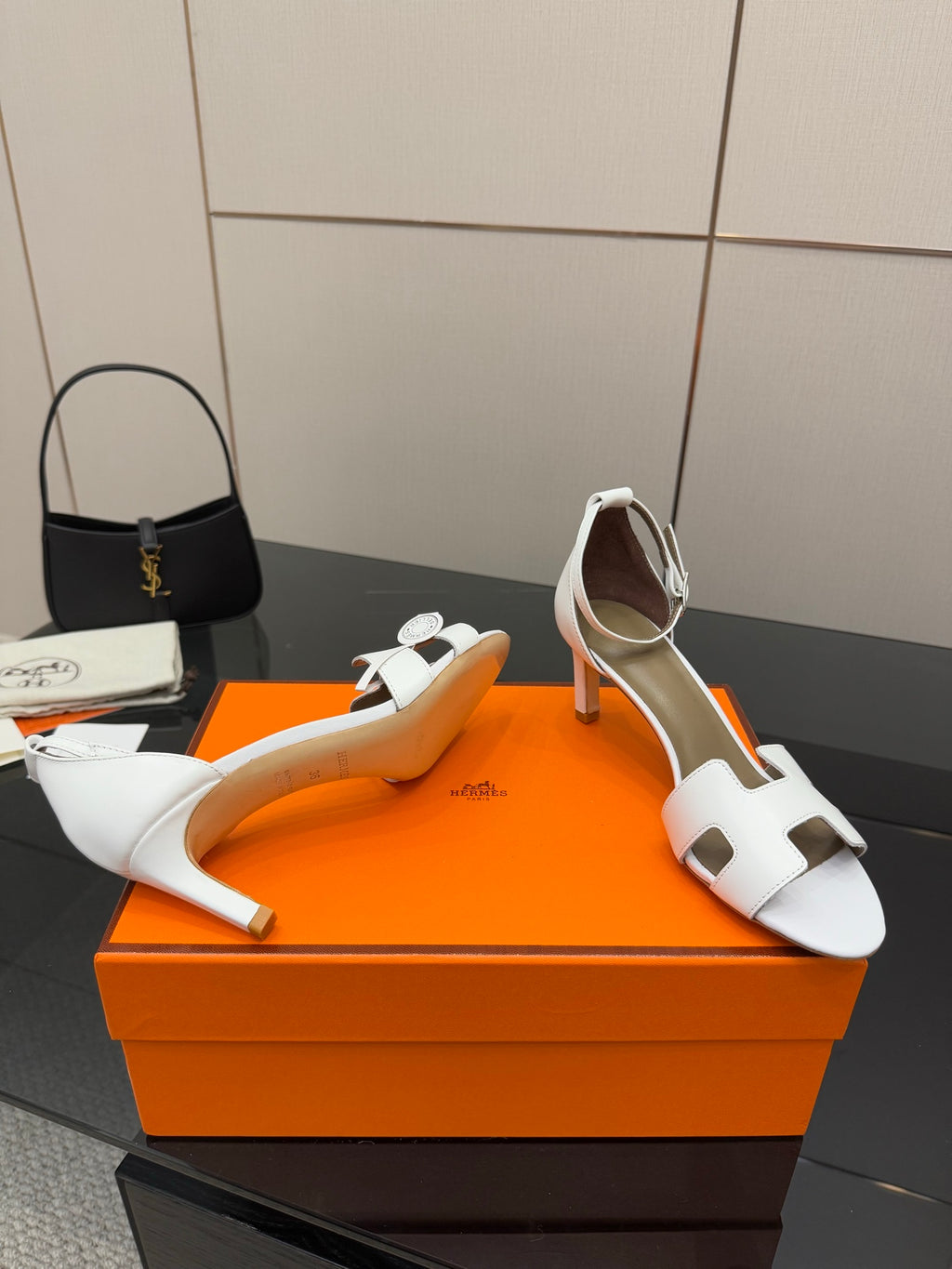 Hermes white leather heeled sandals with cutout strap, shown on orange gift box