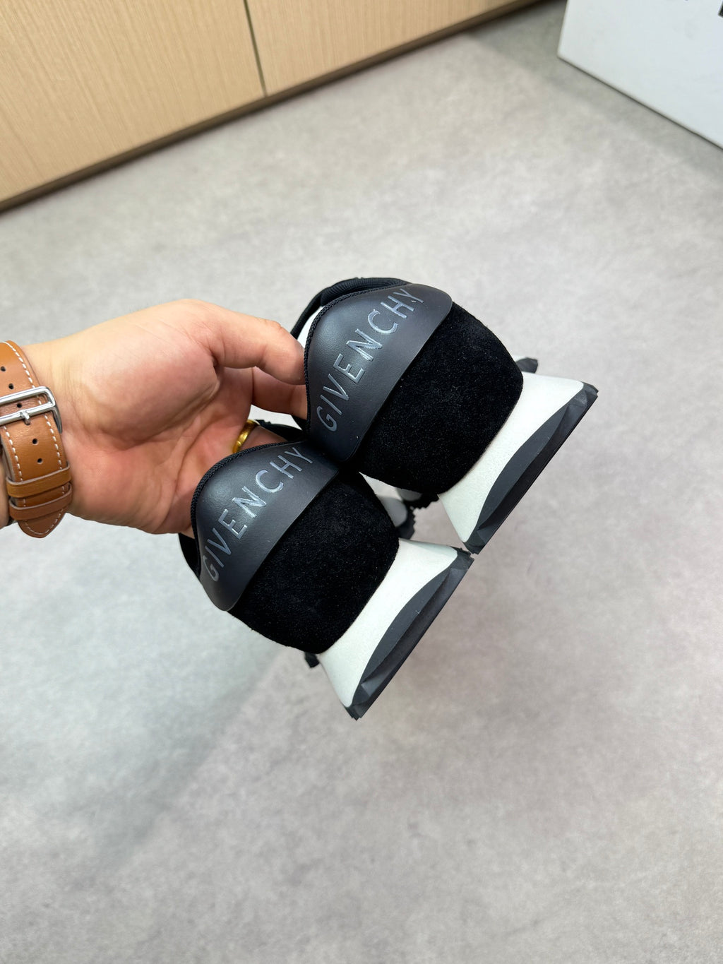 Givenchy black sneakers, held by heel with logo detailing on the tongue