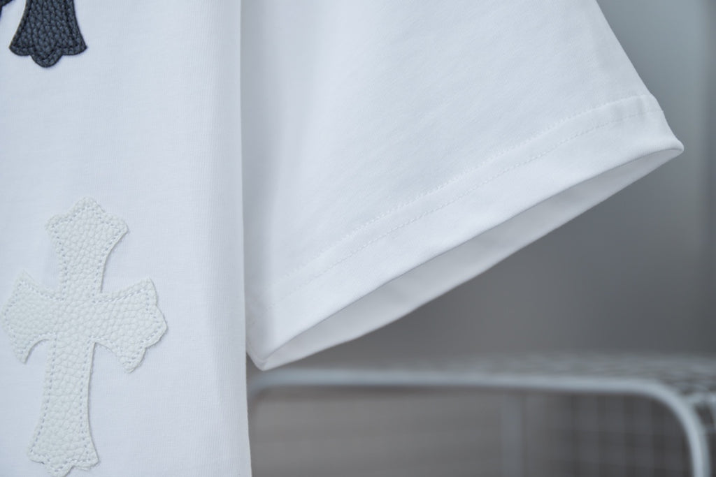White T-shirt fabric detail with dark cross appliques on front