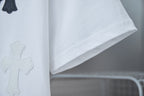 White T-shirt fabric detail with dark cross appliques on front