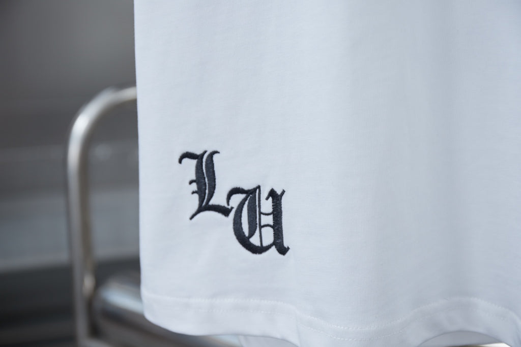 White T-shirt sleeve hem with dark monogram-style logo