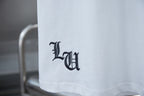 White T-shirt sleeve hem with dark monogram-style logo