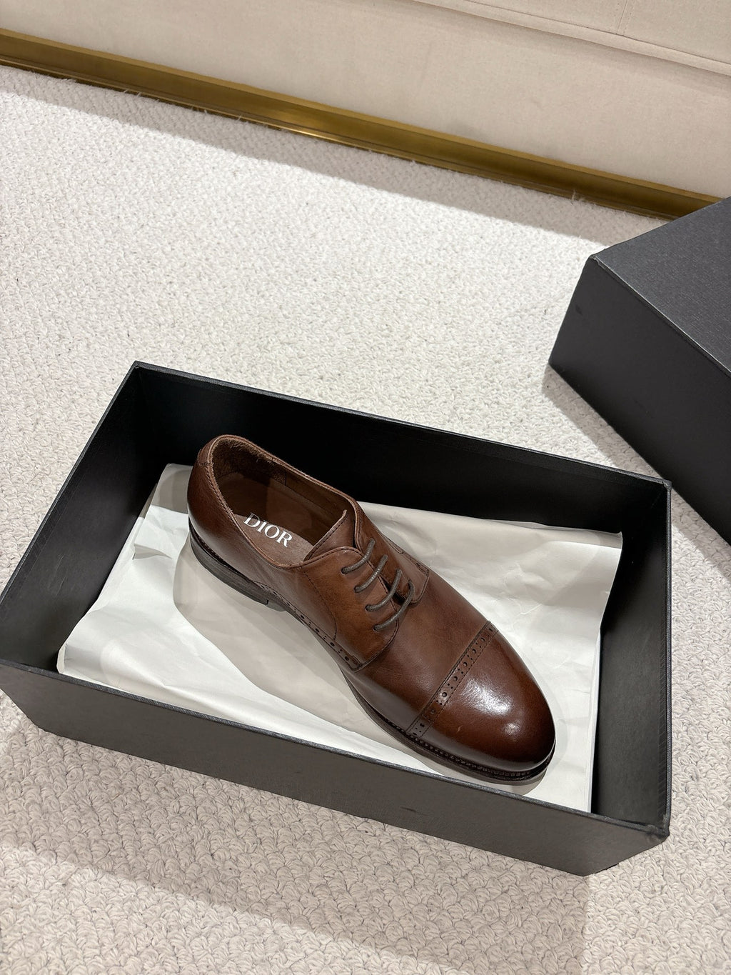 Brown leather lace-up dress shoe in black box with another shoe inside