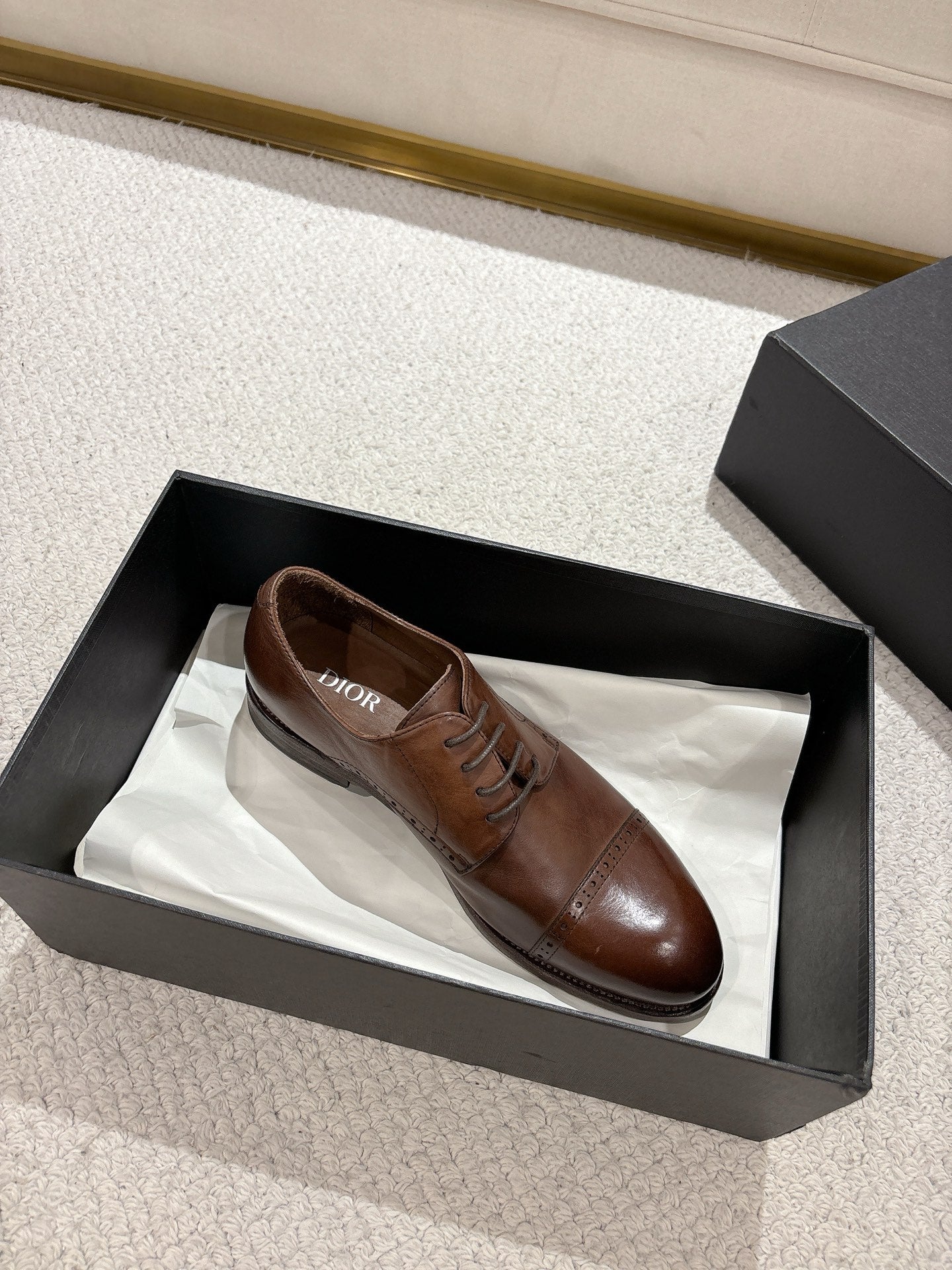 Brown leather lace-up dress shoe in black box with another shoe inside