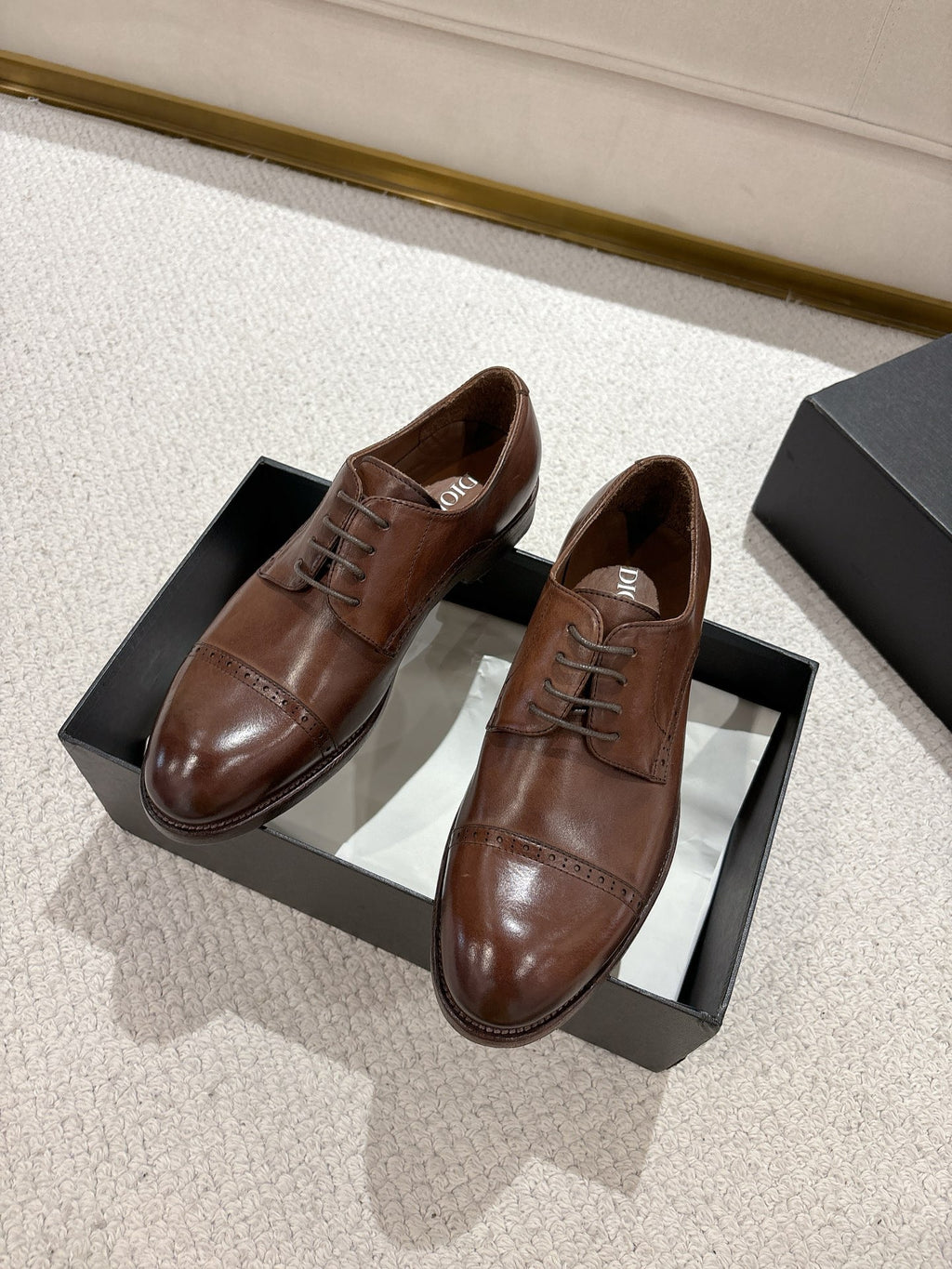 Brown leather lace-up dress shoes with pointed toe, on black shoe box