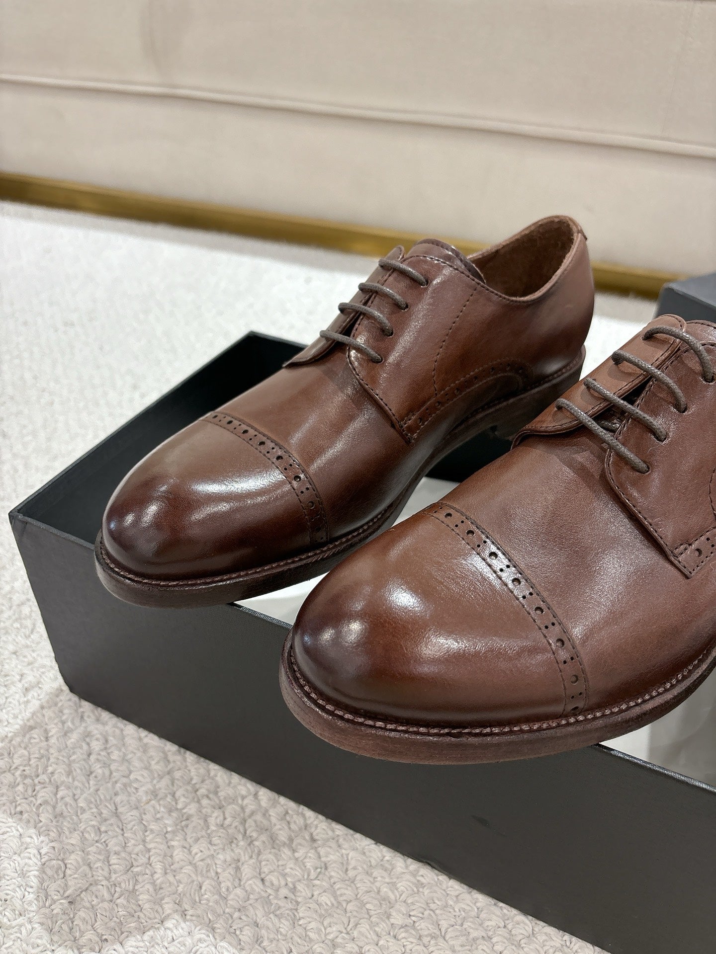 Brown leather lace-up dress shoes with stitched panels, on black box