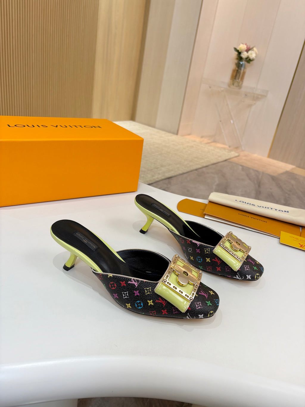 Two ladies mules on display with monogram canvas, gold buckles, neon green heels