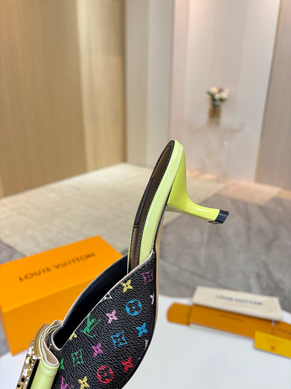 Ladies mule side view with monogram canvas and gold buckle, neon green heel