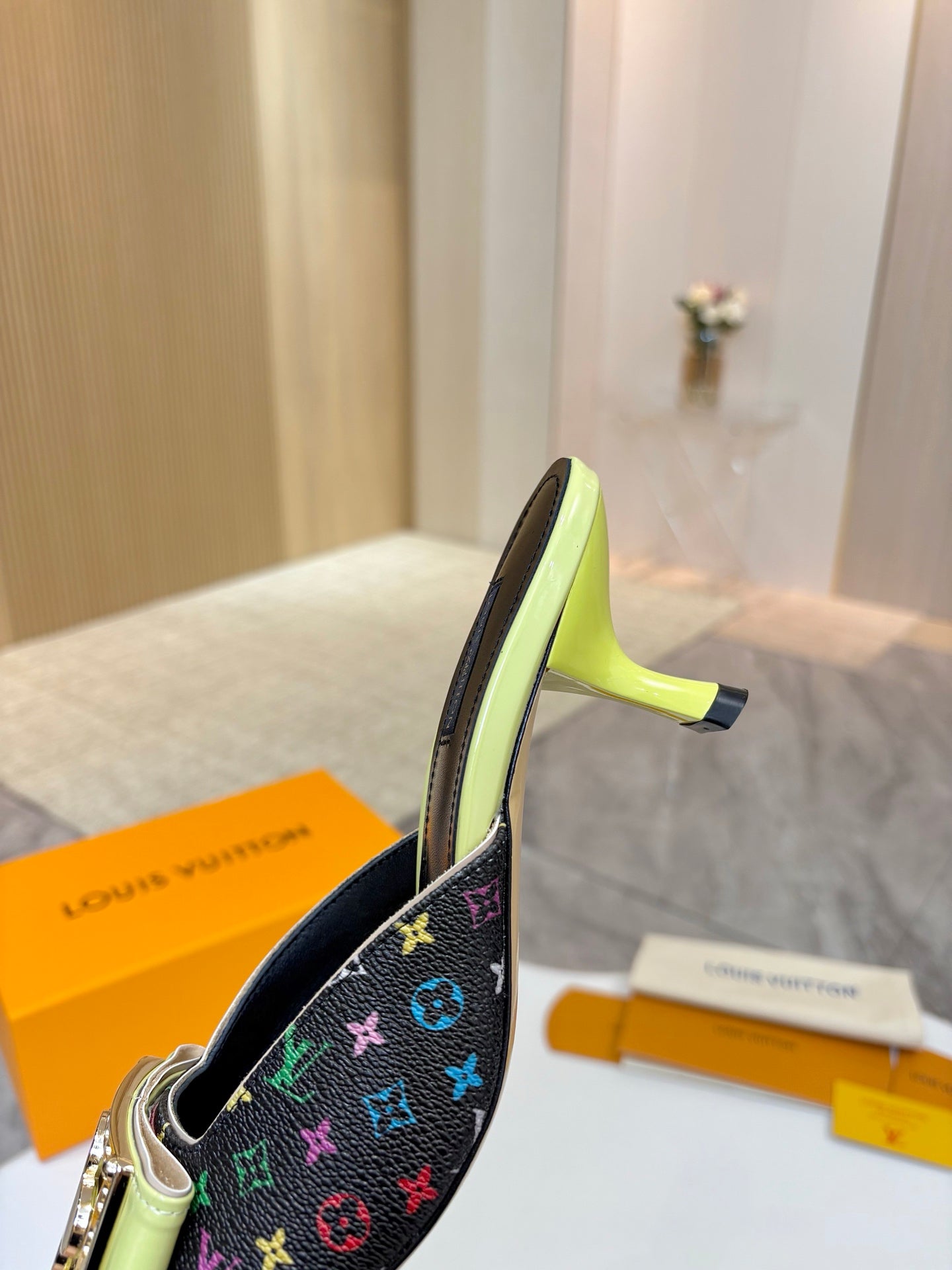 Ladies mule side view with monogram canvas and gold buckle, neon green heel