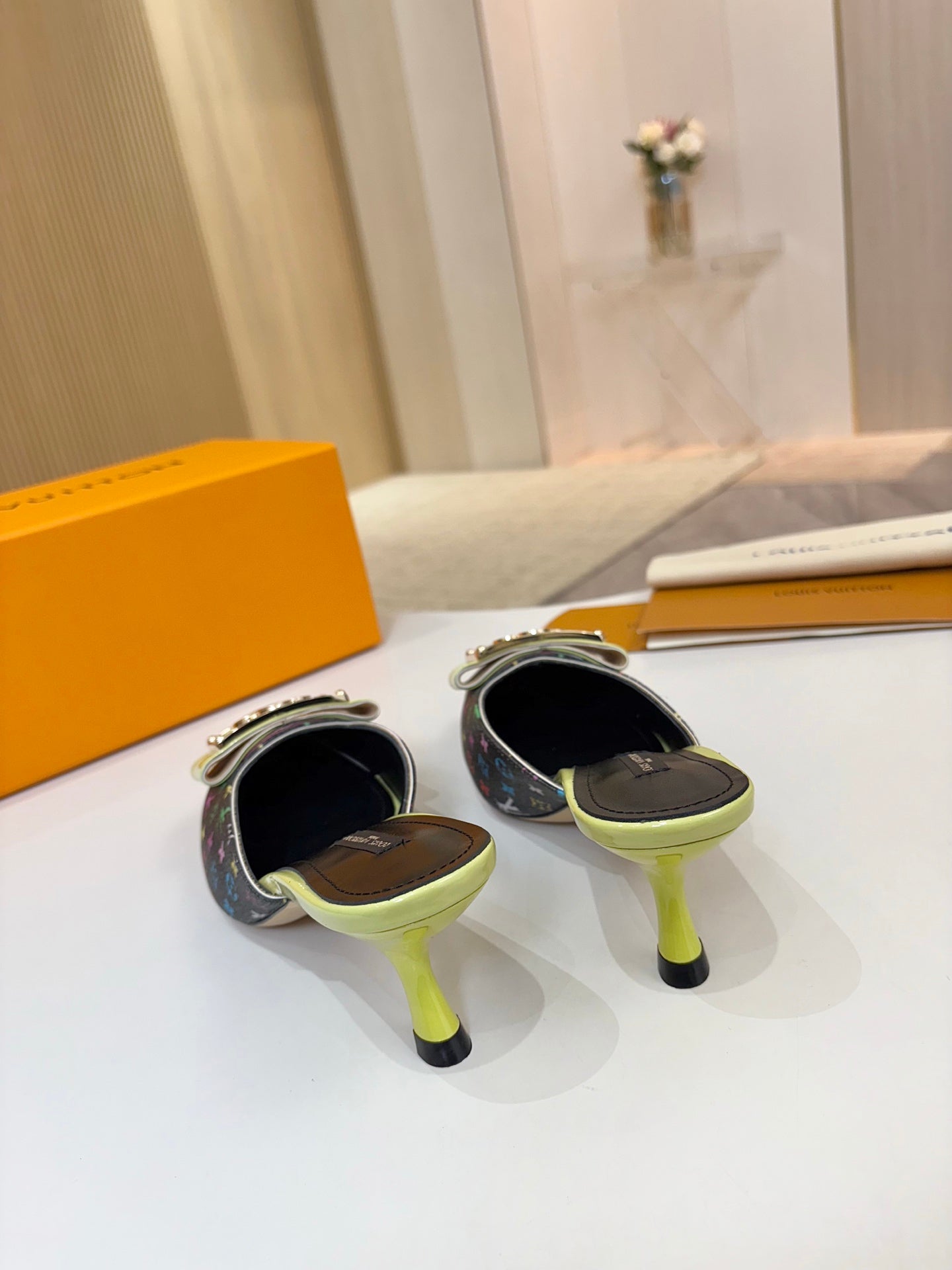 Back view of ladies mules with neon green heels and black footbeds