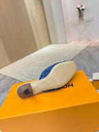 Women's blue monogram mule shoes showing outsoles on orange box