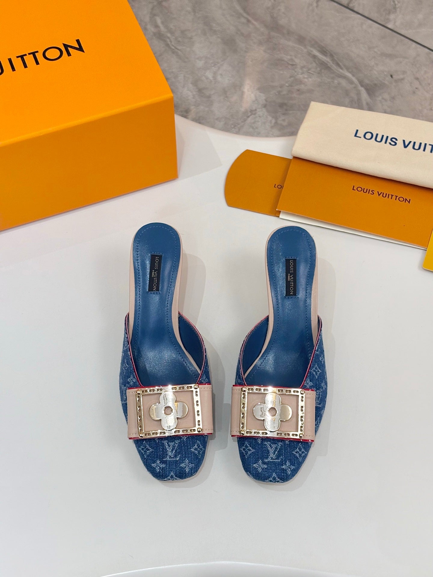 Pair of women's blue monogram mules with gold buckle accents